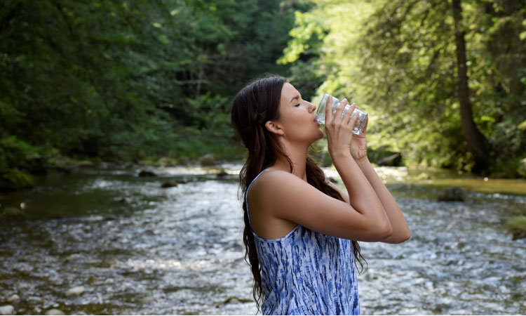 woman drinking water at the river to keep her saliva protecting her teeth