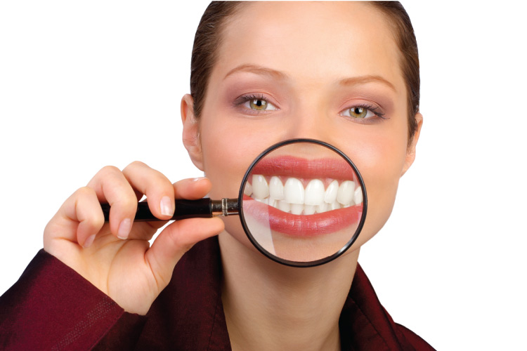 woman holding a magnifying glass in front of her white smile