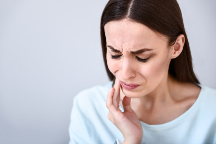 woman grimacing holding her mouth in pain with a cracked tooth