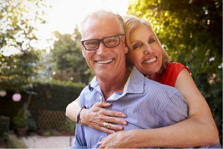older couple hugging and smiling knowing they don't have periodontal disease
